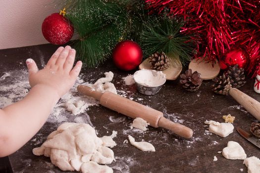 little girl's hand makes christmas cookies, christmas background, bright colors, red christmas tree decorations, copy space