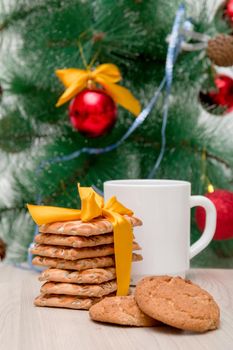 festive cookies and a white cup on a background of a decorated Christmas tree, christmas background, new year 2020