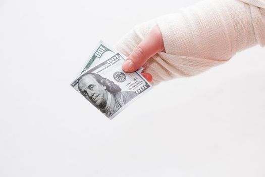 female hand in a bandage holds 100 dollars