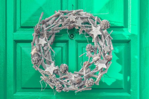 Christmas decoration. Silver wreath hanging on the green door.