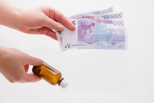 female hands holding a bottle of medicine and euro notes on a white background