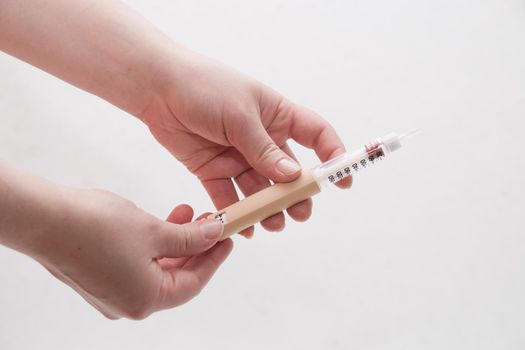 female hands holding a syringe a pen for insulin injection to a patient with diabetes white background