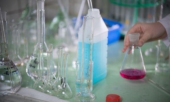 Table full of chemicals and flasks. Chemical lab. A hand touching a flask. Close up table