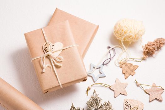 eco friendly gift box packaging for christmas or new year, wooden christmas toys, box wrapped in kraft paper with a spruce branch and a wooden heart on a white background