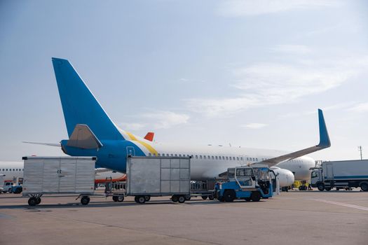 Airfield tractors near big modern airplane ready for boarding in airport hub on a daytime. Plane, shipping, transportation concept