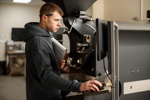 Young specialist worker is roasting coffee in hangar