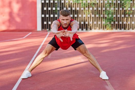 athletic man in red jersey on the sports ground exercise. High quality photo