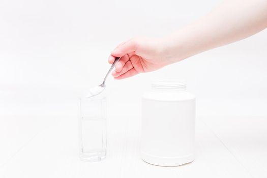 jar and glass of water on a white background, a hand holds a spoon and pours powder into a glass of water, absorbent treatment concept