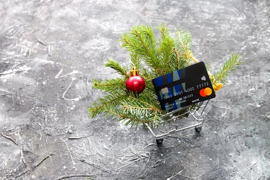 concept of online shopping before christmas, bank card in kozin for purchases on a black background, new year's decor