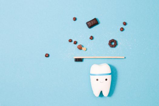 tooth model on a blue background, bamboo tooth puppy and miniature sweets, tooth decay concept, daily oral hygiene and protection against bacteria