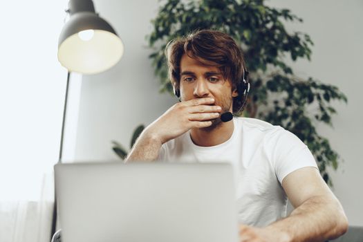 Young man businessman with headset working on laptop from home. Home office concept