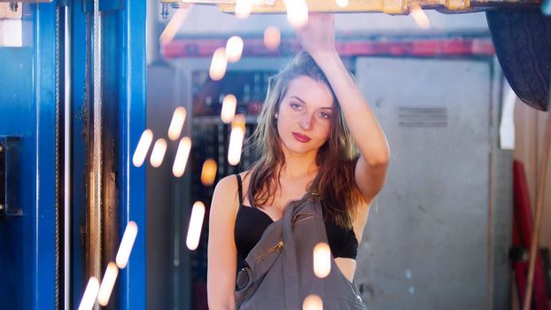 Sexy mechanic girl in car service looking straight. Fire flakes