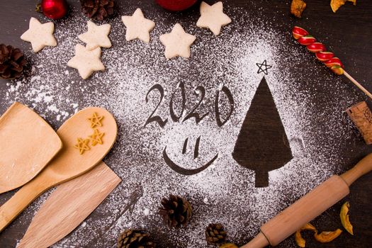 Christmas tree made of flour, Christmas decor, cakes, dough, the process of baking cookies in the shape of stars, kitchen utensils, dark brown wooden table background, Christmas background, copy space, top view