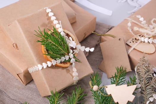 gift box wrapped in eco paper and decorated with dried orange fresh branch of a Christmas tree, natural spruce branches and pine cones for decorating gifts in eco style