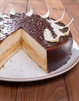 Cut chocolate cake on plate on wooden table close up