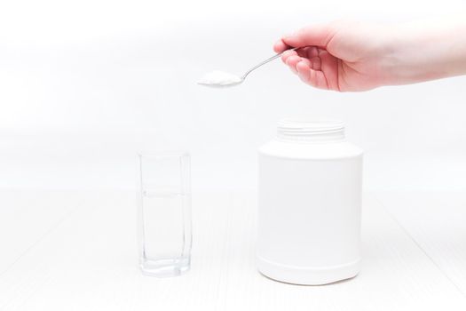 jar and glass of water on a white background, a hand holds a spoon and pours powder into a glass of water, absorbent treatment concept