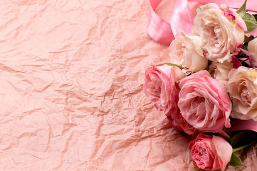 A bouquet of beautiful roses on a pink craft background with space for text.