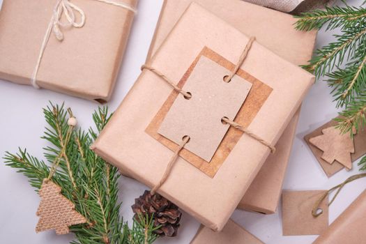 gift box wrapped in eco paper and decorated with homemade greeting tags and paper rope, natural spruce branches and pine cones for decorating gifts in eco style