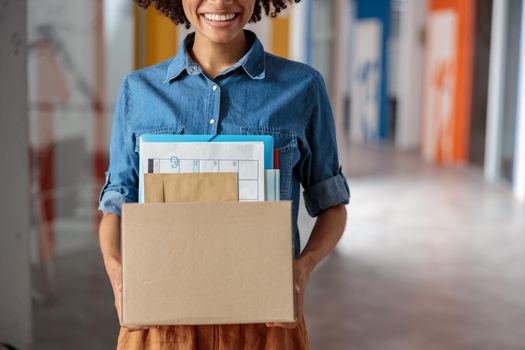 Cropped photo of smiling Afro American woman standing in the office while holding box, copy space