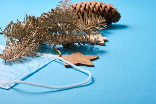 christmas decoration fir branches, fir cones And medical protective mask and on blue background, 2021 concept