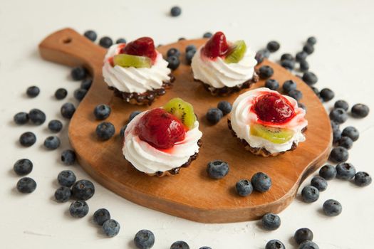 fresh cupcakes with cottage cheese and blueberries on vintage tray-tasty muffin with strawberry and kiwi on wooden plate