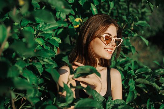 smiling woman wearing sunglasses green leaves nature fashion. High quality photo