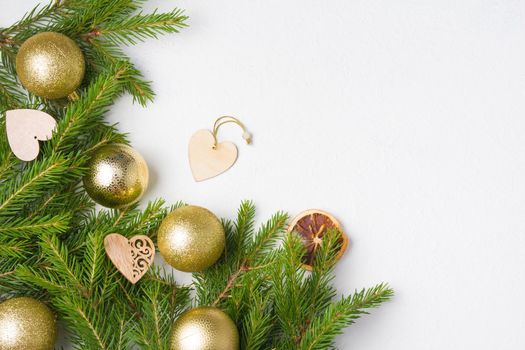 christmas tree golden balls and natural fir branches on a white background top view copy place, wooden eco friendly Christmas tree toys on fresh spruce branches