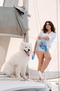 a happy woman with a big white dog on a white yacht in the sea.