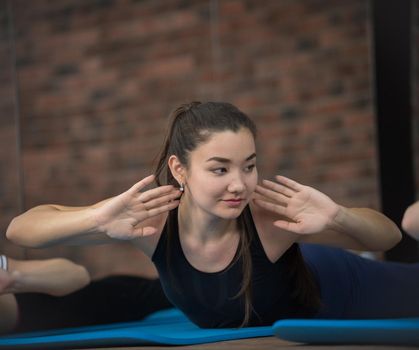 Pole dance studio, Group of women doing stretching, twisting on stomach, on background wall brick. Wellness and Healthy Lifestyle. Portrait