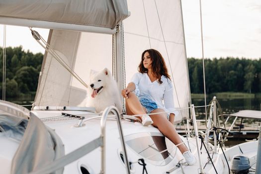 a happy woman with a big white dog on a white yacht in the sea.