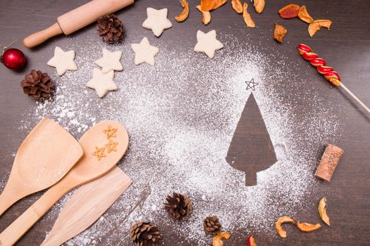 Christmas cookies in the shape of stars, dough for bees, kitchen scoops and rolling pin, top view, silhouette of a Christmas tree made from flour, top view, copy space