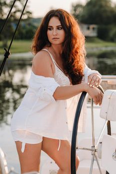 sexy woman in a white shirt enjoys the sunset on her private white yacht.