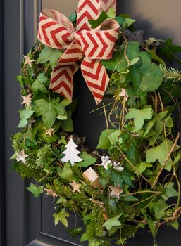 Front door with a Christmas wreath of ivy and bows.