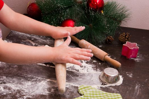 rolling pin child rolls dough for christmas cookies, new year, holiday background