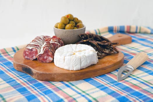 simple snack with camembert cheese, olives and bread with ham on fabric blue background, tasty cheese background in retro style