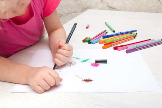 little girl draws flowers on paper with felt-tip pen copy place at the table, children development