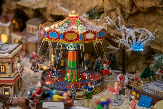 Amusement park in miniature with carousels in winter with figurines