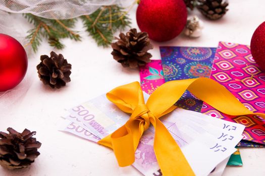 Euro banknotes tied with a gold ribbon with a bow on envelopes for money, white background, Christmas, New Year