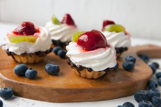 fresh cupcakes with cottage cheese on vintage tray-tasty muffin with strawberry and kiwi on wooden plate