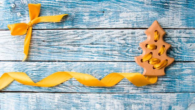 wooden flat toy tree with a gold ribbon on a blue wooden background, copy space, top view