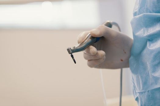 Dentist's bloody hands with drill in dental office, close up