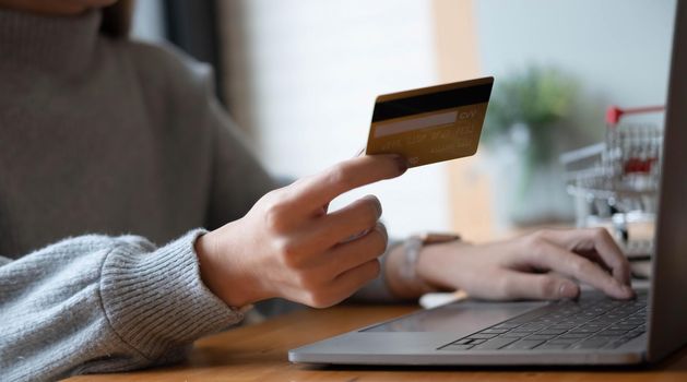 Online payment,Young woman's hands using computer and hand holding credit card for online shopping.