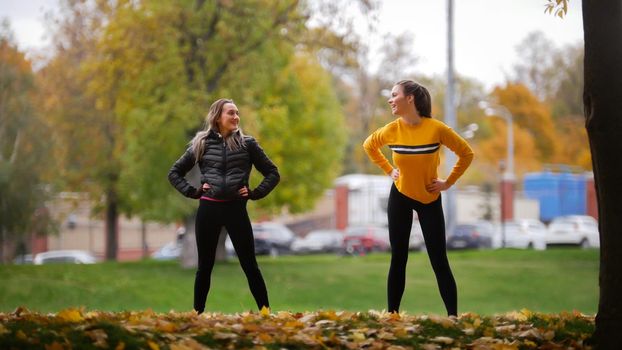 Girls warming up outside before training in park. Hands to the sides. Autumn. Fall