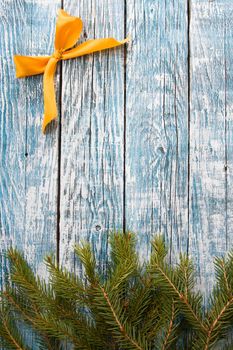 fir branches and golden ribbon bow on a blue wooden background, copy space top view