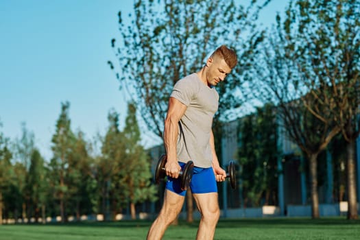 athletic man training with dumbbells in the morning Park. High quality photo