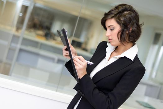 Portrait of a business woman in an office. Businesswoman writting with a folder in her hands in a modern office.