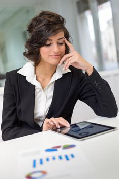 Portrait of a business woman looking at her tablet computer. Businesswoman in a modern office.