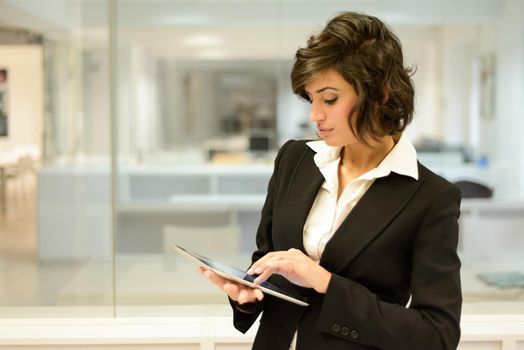 Portrait of a business woman looking at her tablet computer. Businesswoman in a modern office.