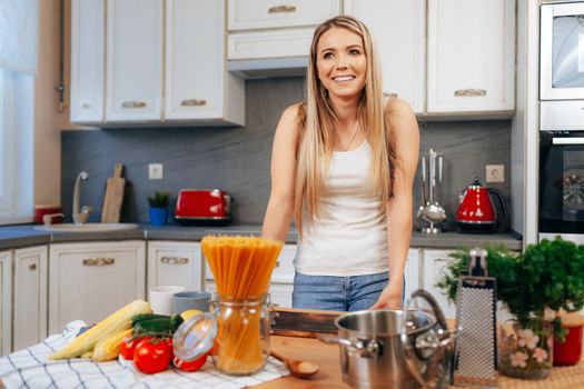 Smiling young woman cooking something at her kitchen at home