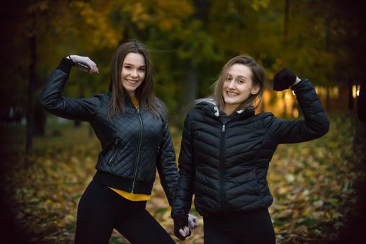 portrait of two girls in black jackets in autumn forest. telephoto shot